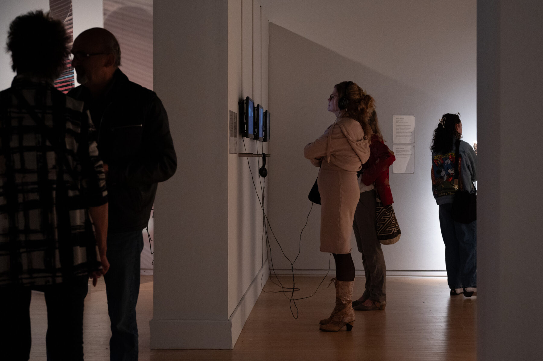 Two women observe a mixed media installation mounted on the wall of the gallery.