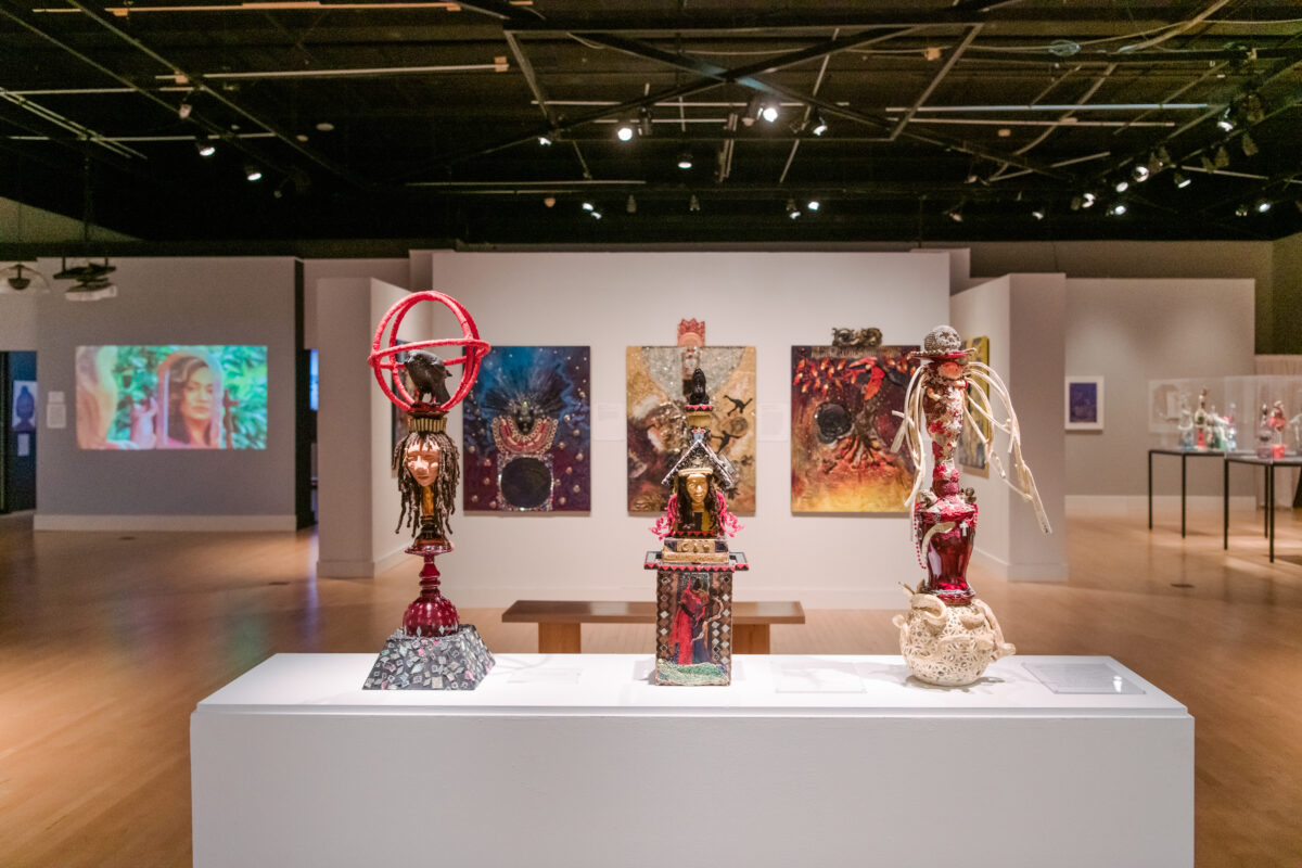 Installation view of Oletha DeVane: Spectrum of Light and Spirit. Three mixed media sculptures stand on a rectangular pedestal.
