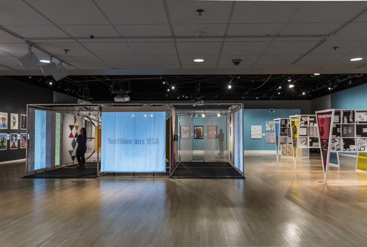 Installation view of a large gallery space filled with free-standing geometric structures providing didactic information to guests.