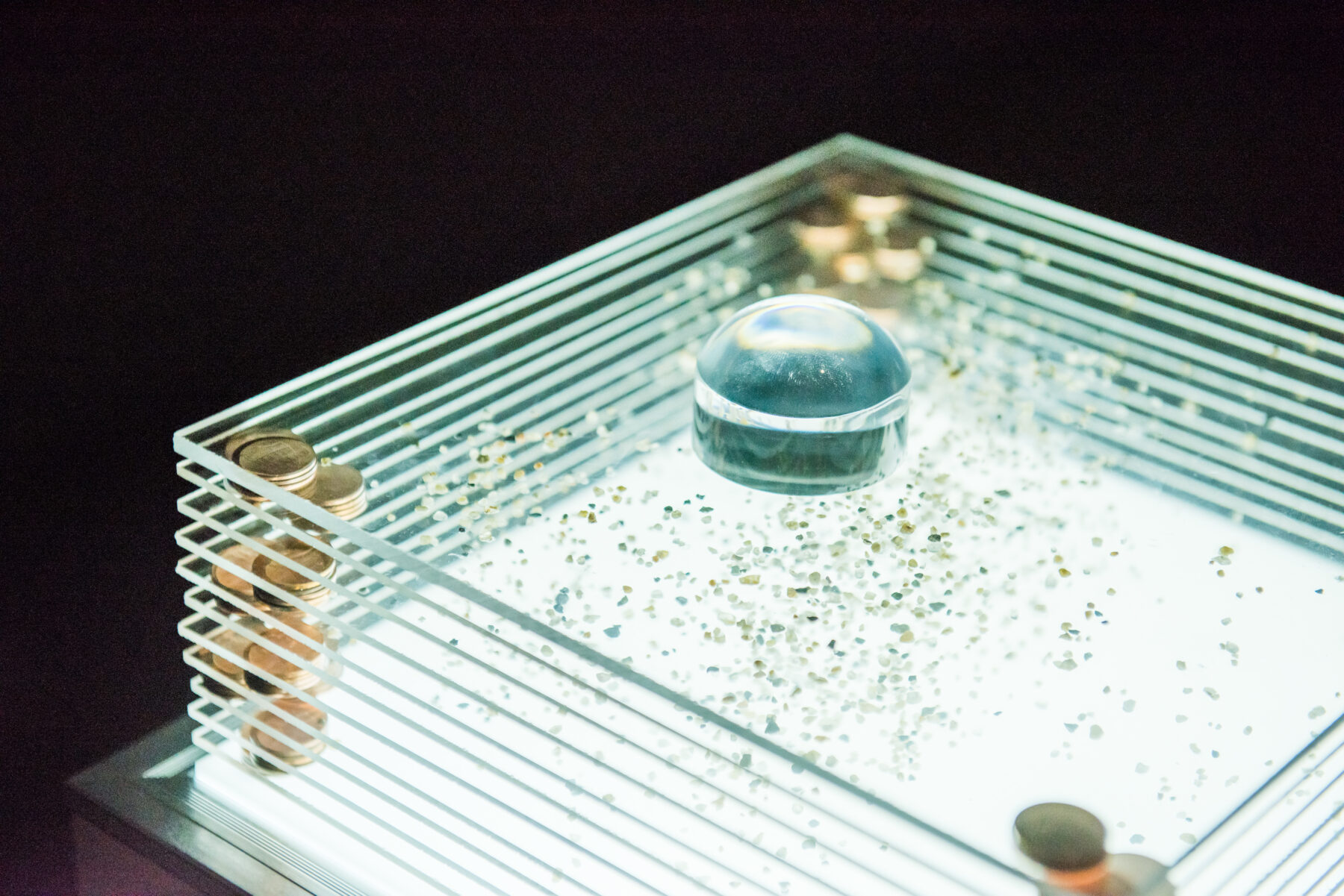 Detail of a glass and mixed media sculpture on an illuminated pedestal.