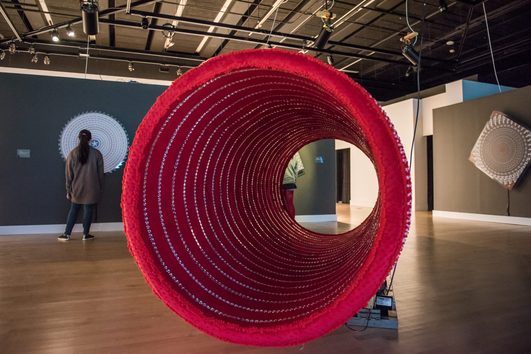 A large red tube sculpture occupies most of a gallery space.