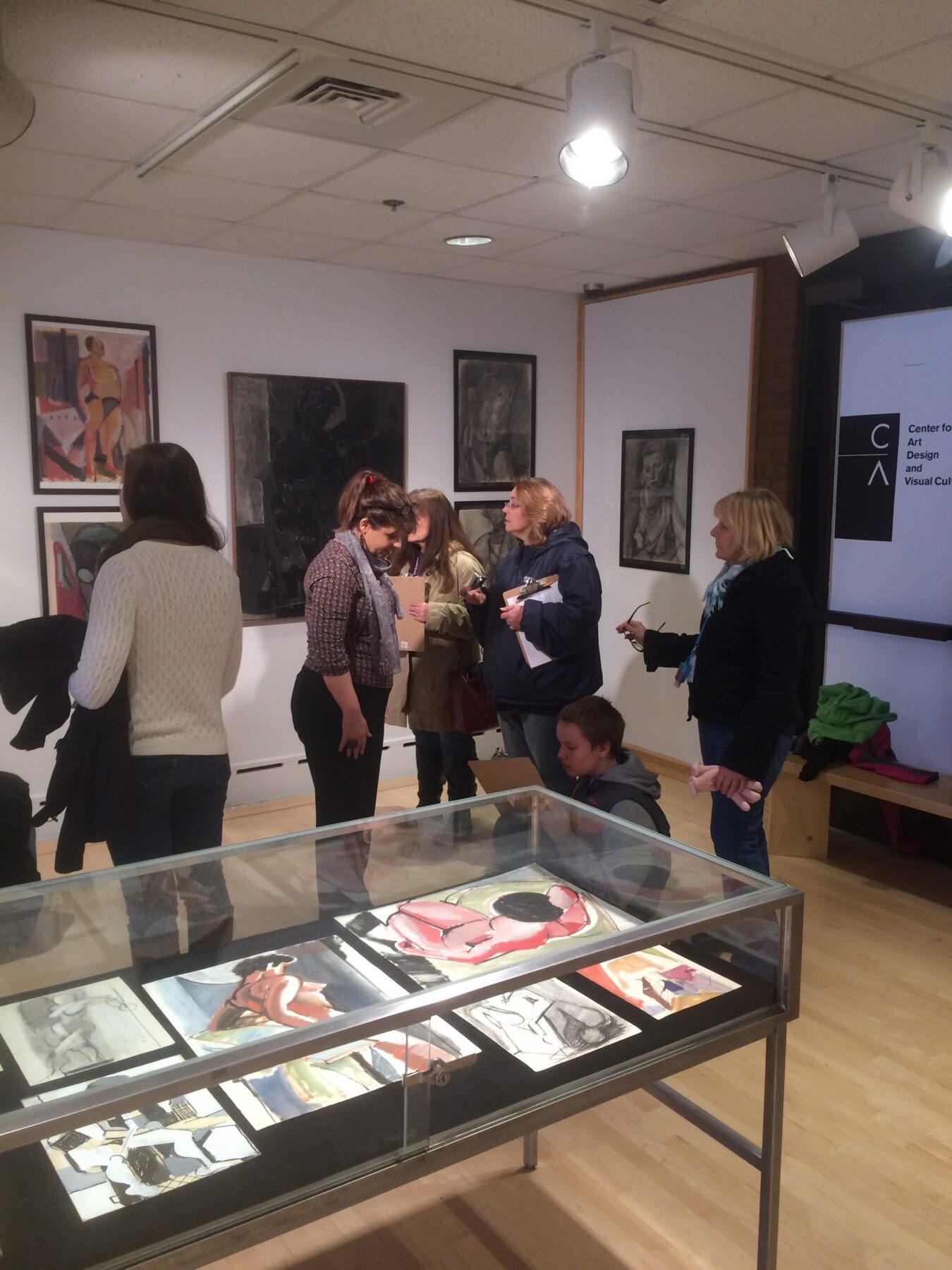 People standing and observing artworks in a gallery exhibition.