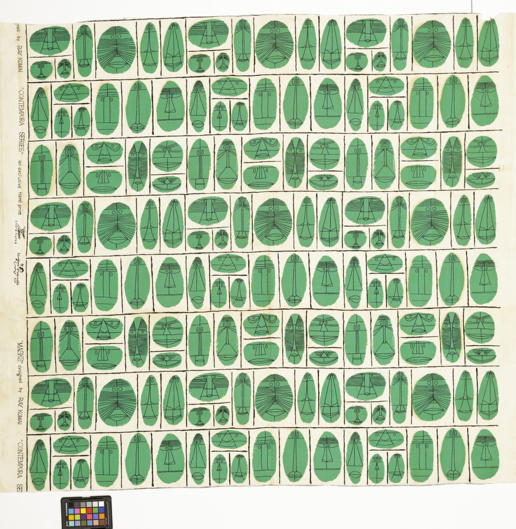 A portion of wallpaper featuring kelly green masks on a white background. They are arranged in a decorative grid pattern.