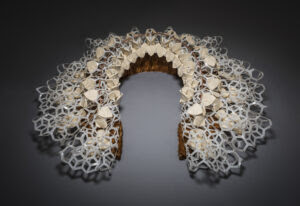 A large white lace Elizabethan collar is photographed from above against a dark grey background.