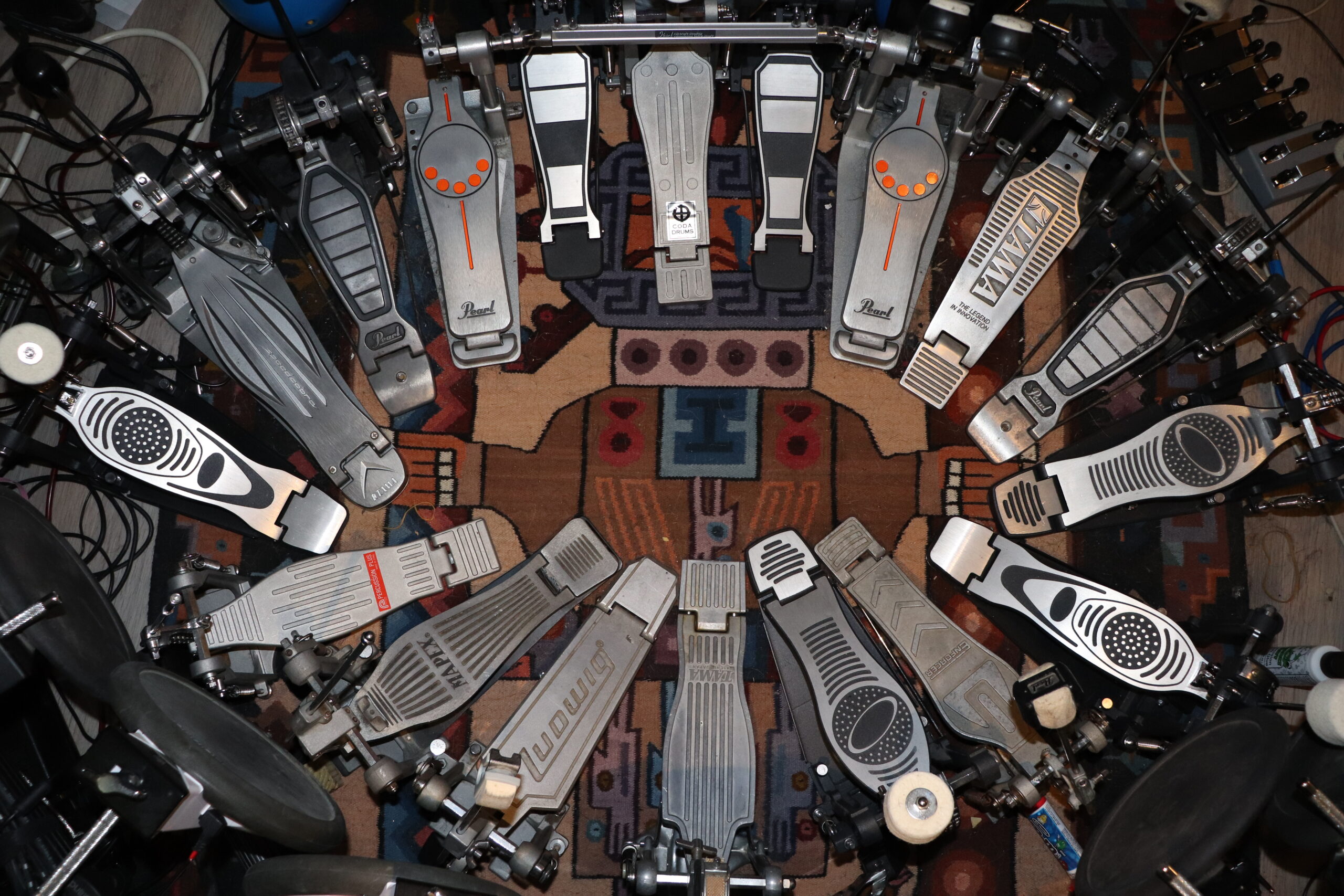 A photograph of guitar pedals arranged in a circle atop a geometric rug.