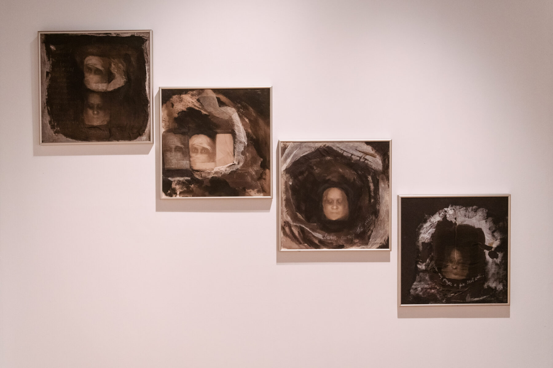Installation view of Oletha DeVane: Spectrum of Light and Spirit. Four square monochromatic works are hung on the wall, descending from right to left in height.
