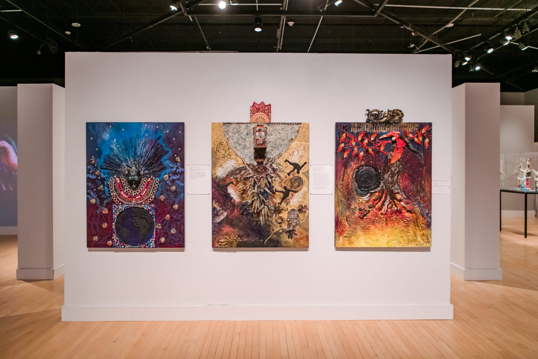 Installation view of Oletha DeVane: Spectrum of Light and Spirit. Three mixed media works are hung on the wall of a gallery and are photographed straight on.