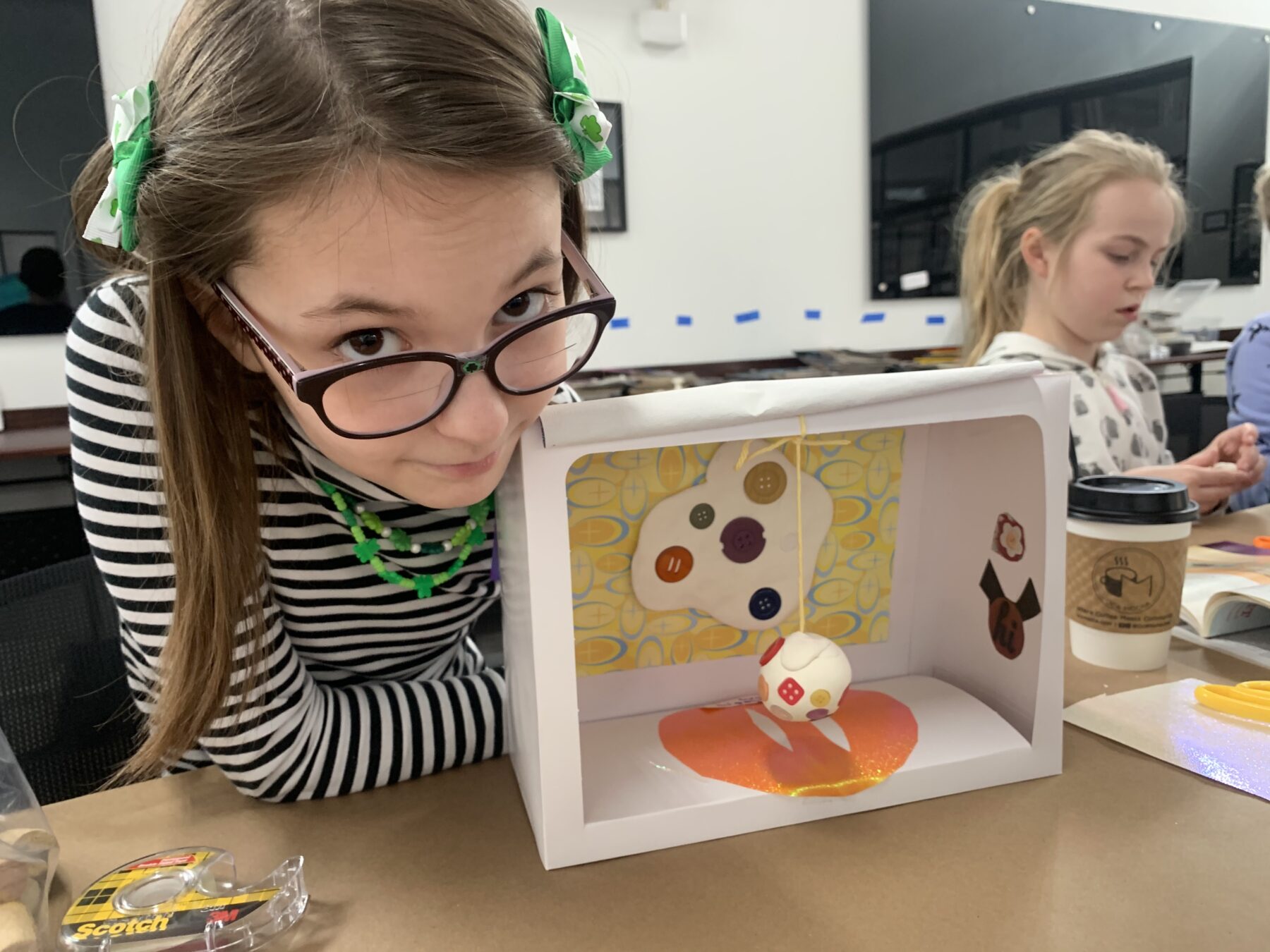 A young OCA Mocha Kids Club artist shows off her Button Museum created at the “Make Your Own Museum” craft event.