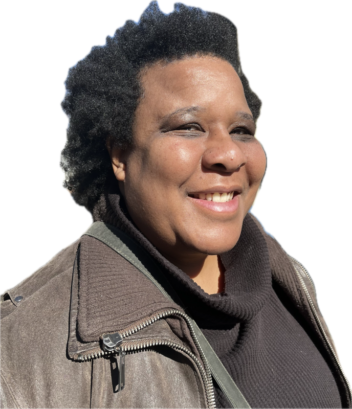 A portrait of a woman with a dark skin-tone. She has a short hair and wears a black shirt and leather jacket. She is smiling for the camera.