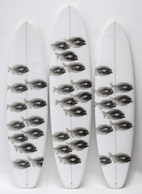 Piranhas Triptych by Steve Miller, 2014. Three surfboards titled Black Piranhas on White displayed left to right: 87.5 x 22 in., 96 x 22 in., and 88 x 21.5 in. Each is a Long Board Diamond Tail featuring black piranha imagery on a white surface. Courtesy of the artist.